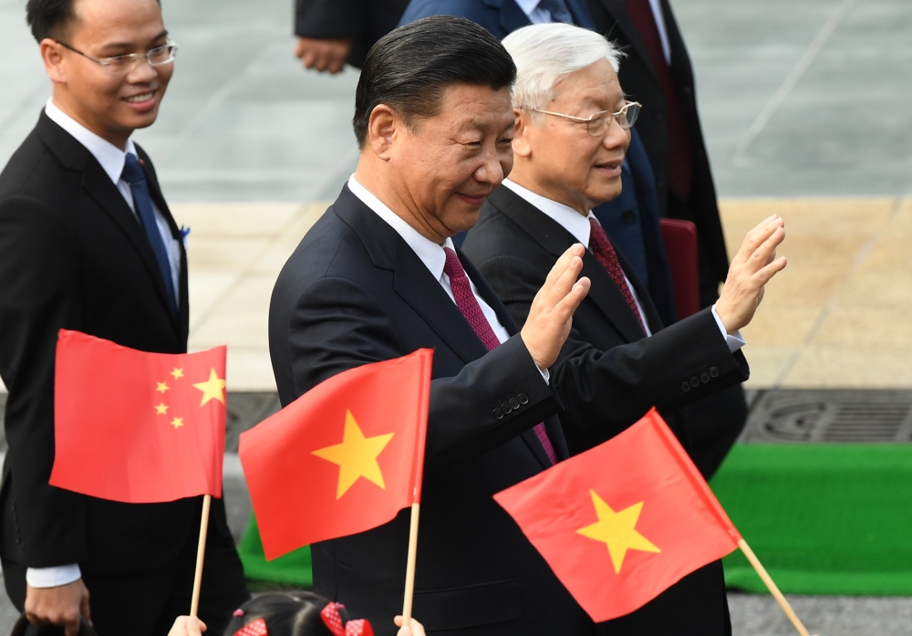 Chinese President Xi Jinping, center, and Vietnam’s Communist Party Secretary General Nguyen Phu Trong, right, wave during a welcoming ceremony at the presidential palace in Hanoi on Sunday. — AFP
