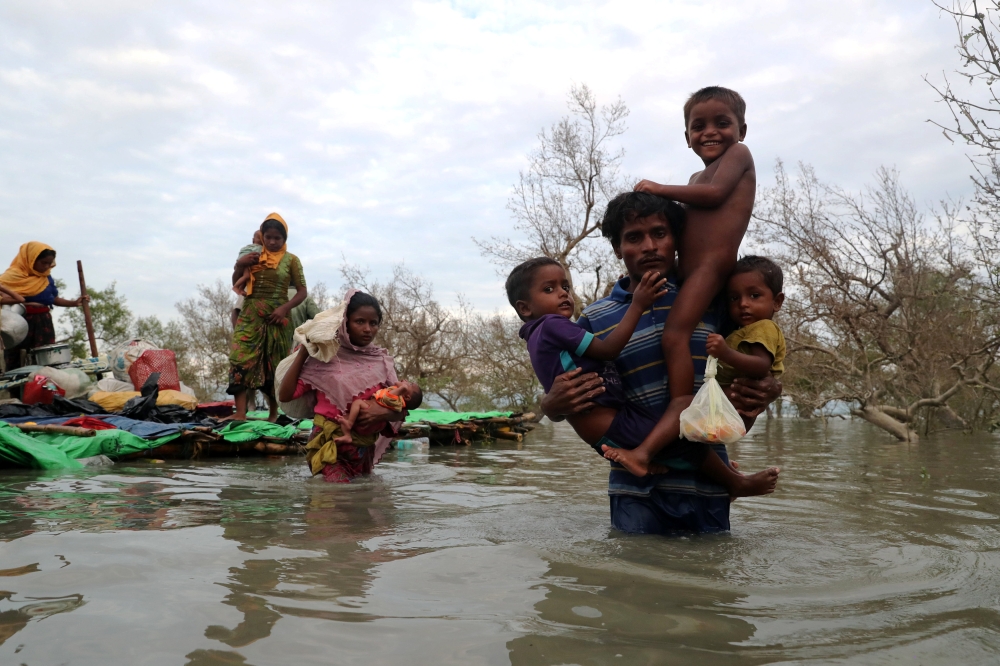 Rohingya refugees cross the Naf River with an improvised raft in Teknaf, Bangladesh, on Sunday. — Reuters