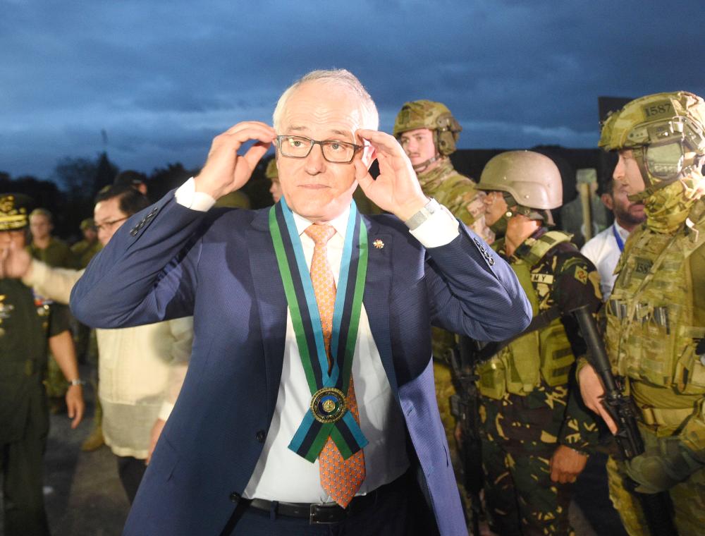 Australian Prime Minister Malcolm Turnbull, center, adjusts his glasses as he speaks with members of the media during a visit to the military headquarters in Quezon City, Philippines, on the sidelines of the Southeast Asian Nations (ASEAN) Summit on Monday. — AFP