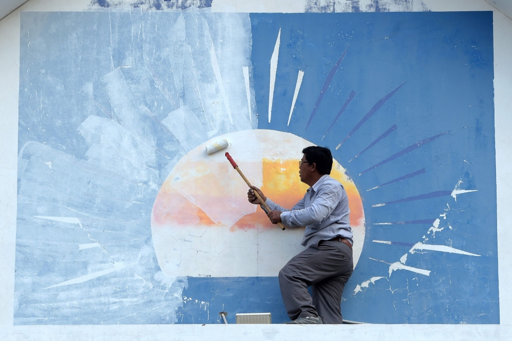 A supporter of the opposition Cambodia National Rescue Party (CNRP) paints over the party logo at the CNRP headquarters in Phnom Penh on Saturday. — AFP