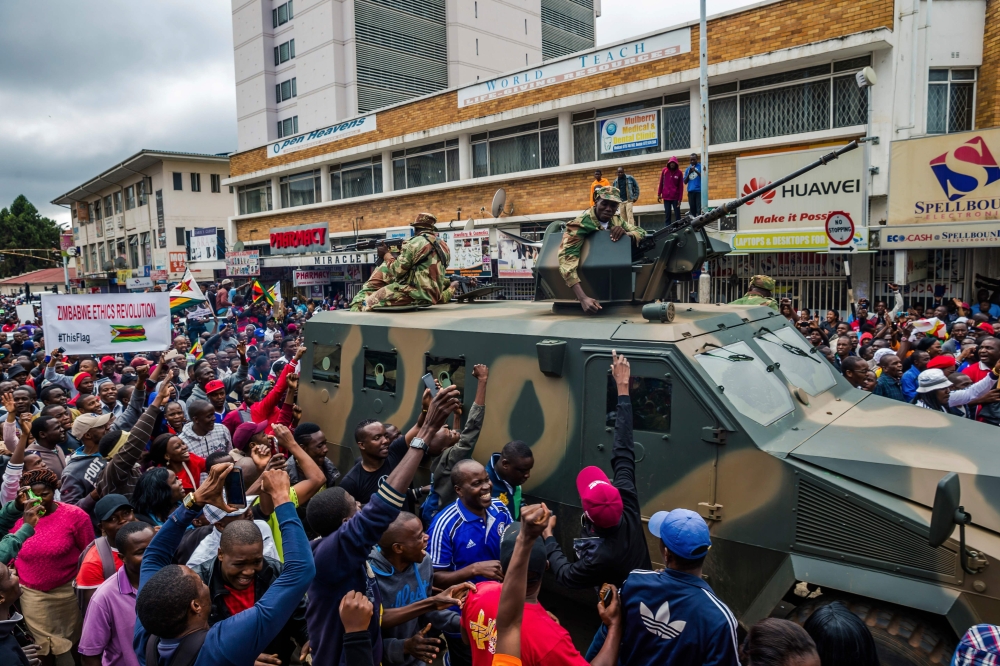 People cheer a passing Zimbabwe Defense Force military vehicle during a demonstration demanding the resignation of Zimbabwe’s president in Harare on Saturday. — AFP