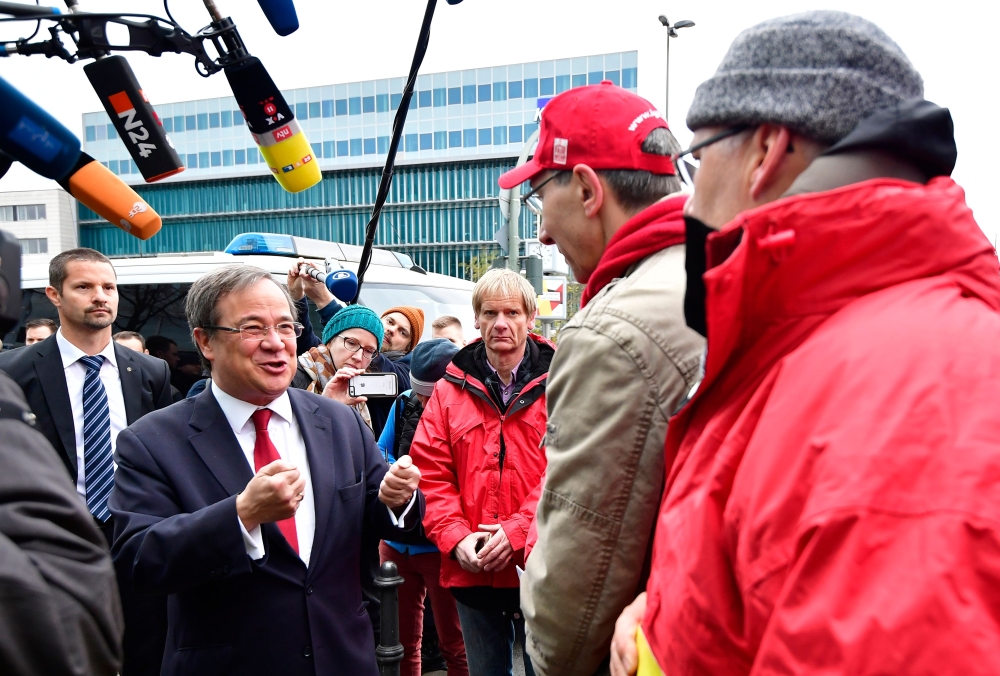 Christian Democratic Union (CDU) party’s state leader in North Rhine-Westphalia Armin Laschet chats with protesters as he arrives for further exploratory talks with members of potential coalition parties to form a new government in Berlin on Saturday. — AFP