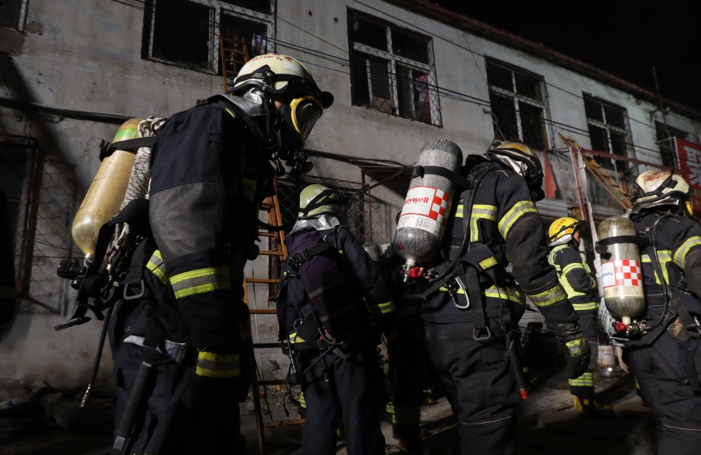 Chinese firemen gather around a house where a fire tore through it in Beijing on Saturday. — AFP
