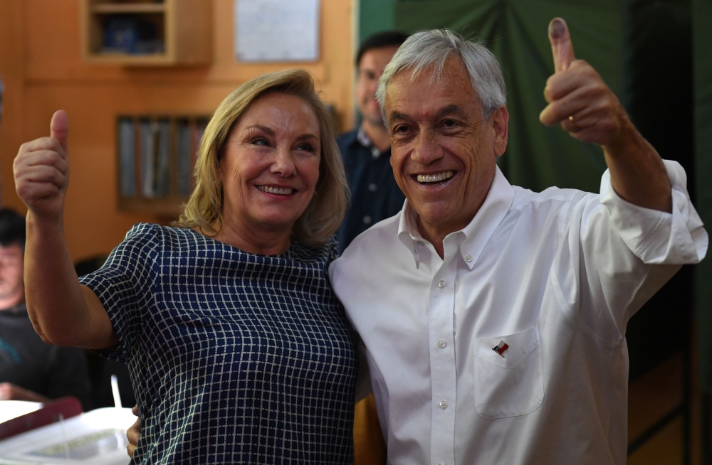 Chilean presidential candidate Sebastian Pinera, right, stands next to his wife Cecilia Morel, after casting his vote during the presidential election in Santiago on Sunday. — AFP