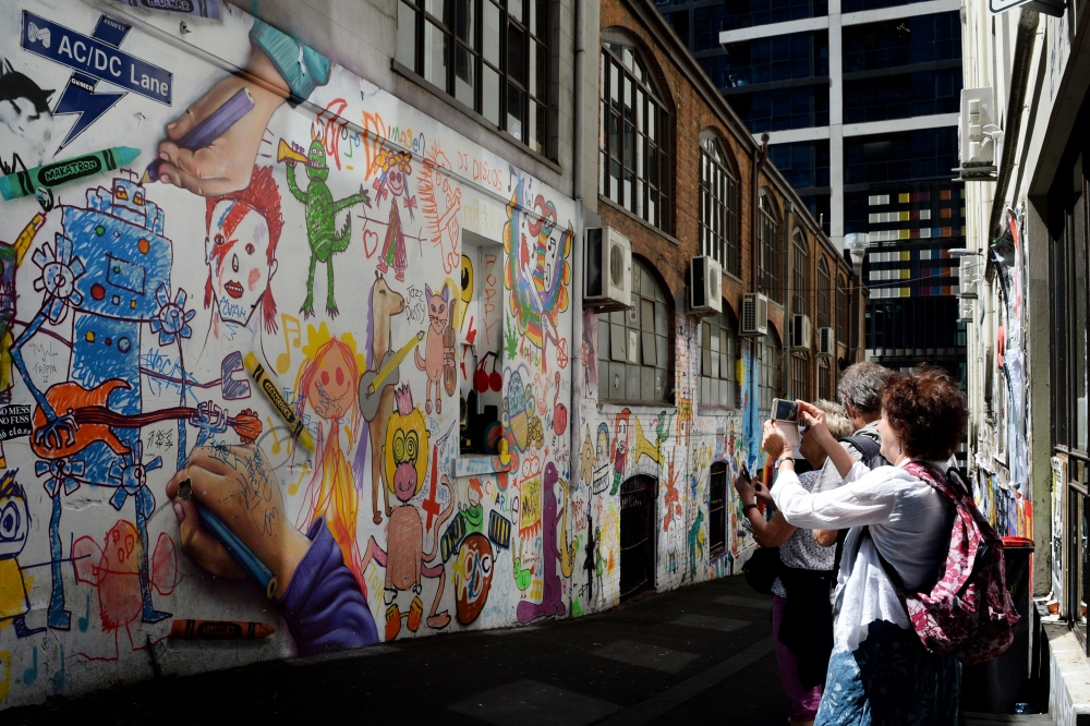 People take photographs in AC/DC Lane in Melbourne on Sunday, after the announcement of the death of the band's guitarist Malcolm Young. - AFP