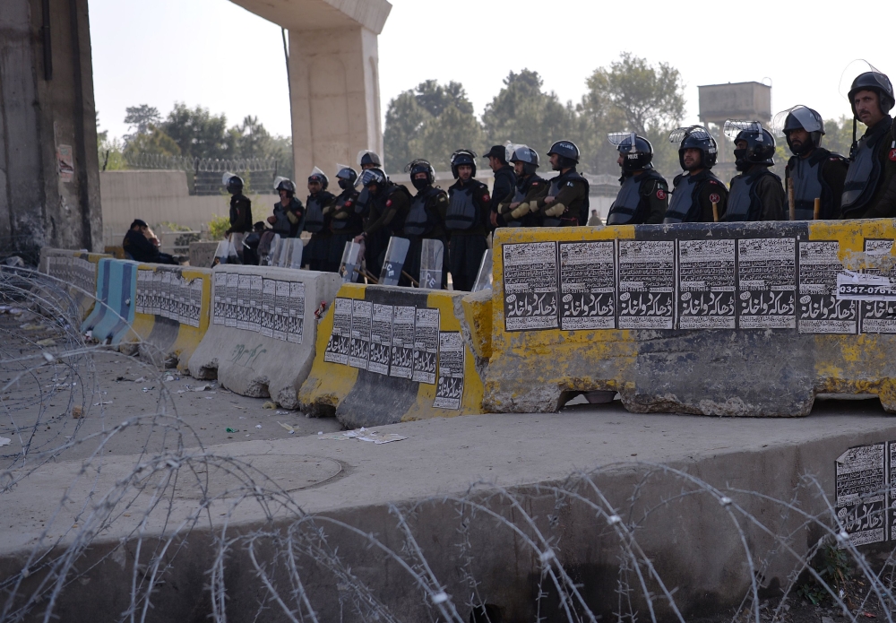 Pakistani police stang guard during a protest by activists from a religious party in Islamabad on Monday. — AFP