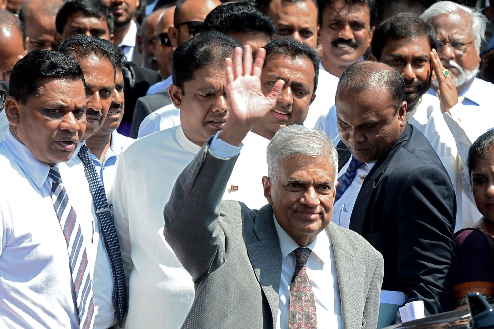 Sri Lanka Prime Minister Ranil Wickremesinghe, center, waves as he leaves a court complex in the capital Colombo on Monday after testifying before a Presidential Commission of Inquiry investigating inside trading allegations against the former central bank governor.  — AFP