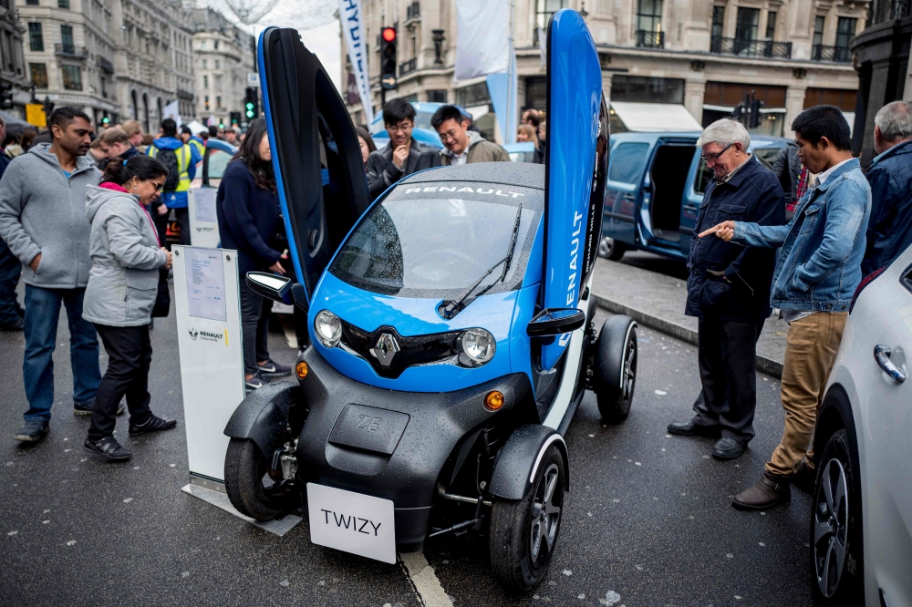 Members of public look at a Renault Twizy electric vehicle (EV) during the Regent Street Motor Show in London. A driverless, electric car is only a swipe away in the cities of the future, where pollution clampdowns and rapid advances in technology will transform the way we travel, despite lagging infrastructure. A switch from petrol to EVs is under way. Britain and France intend to ban the sale of fully petrol or diesel cars from 2040, while smog-plagued India wants to sell only electric cars by 2030. - AFP
