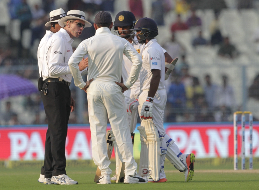 India's captain Virat Kohli, back to camera, Sri Lanka's captain Dinesh Chandimal, second right, and Niroshan Dickwella interact with umpires during the fifth day of their first Test cricket match in Kolkata, India, Monday. — AP