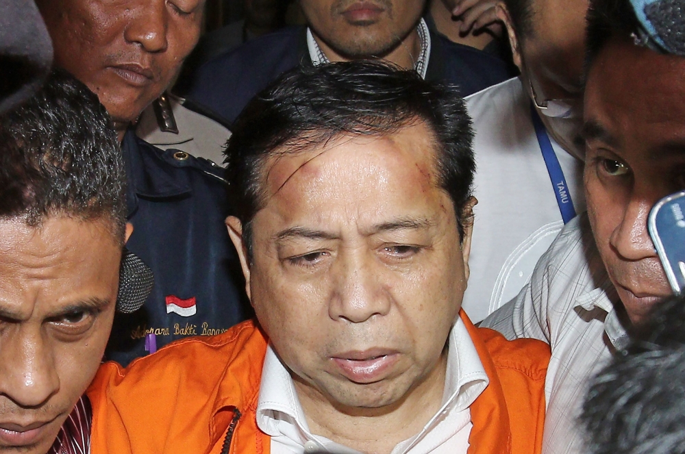 Indonesia’s Parliament Speaker Setya Novanto (in orange) is being escorted by officials from the Corruption Eradication Commission (KPK) in Jakarta on Sunday.  — AFP