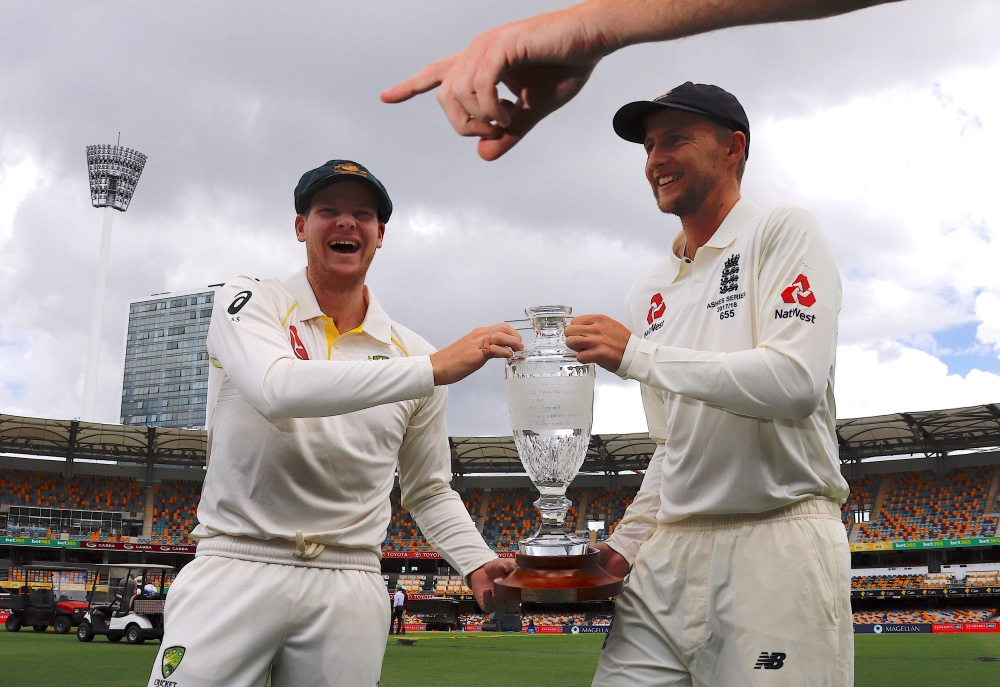 England's cricket team captain Joe Root and Australia's cricket team captain Steve Smith react as they are directed where to stand while holding the Ashes series trophy during an official event ahead of the Ashes opening Test match at the GABBA ground in Brisbane, Australia, on Wednesday. — Reuters