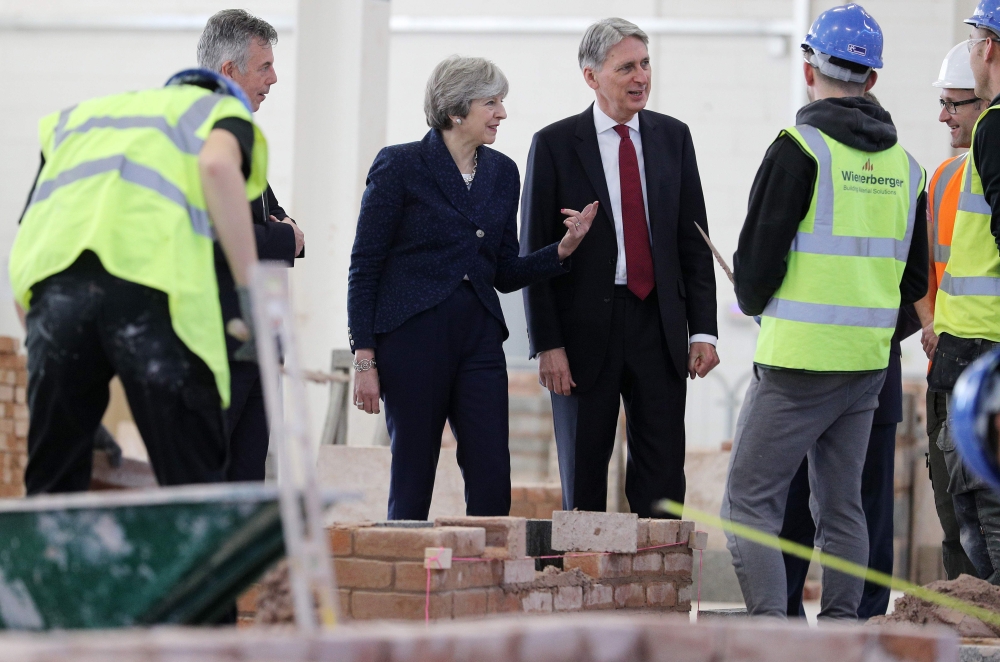 Britain's Prime Minister Theresa May (3L) and Britain's Chancellor of the Exchequer Philip Hammond (C) visit to Leeds College of Building, a specialist further and higher education construction college, in Leeds, northern England, on Thursday. UK economic growth rose in the third quarter thanks to consumer spending, official data showed Thursday, but the data is unlikely to push annual GDP above a gloomy government forecast, as poor productivity and Brexit cloud the outlook. — AFP