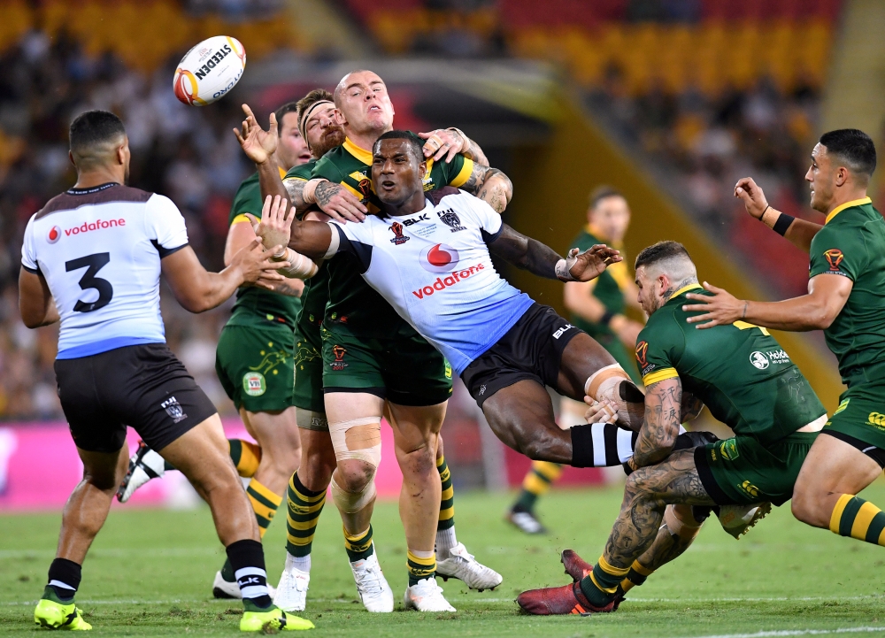 Fiji's Suliasi Vunivalu passes the ball as he is tackled by Australian players during the Rugby League World Cup semifinal match at Lang Park, Brisbane, Australia, on Friday. — Reuters