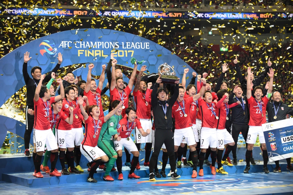 Urawa Red Diamonds' coach Takafumi Hori (C) holds the trophy aloft as he celebrates with his team after they beat Saudi Arabia's Al Hilal to win the AFC Champions League football final in Saitama on Saturday. — AFP