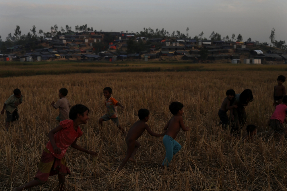 Rohingya refugee children play in a field outside the Moynarghona refugee settlement near Cox’s Bazar, Bangladesh, on Friday. — Reuters