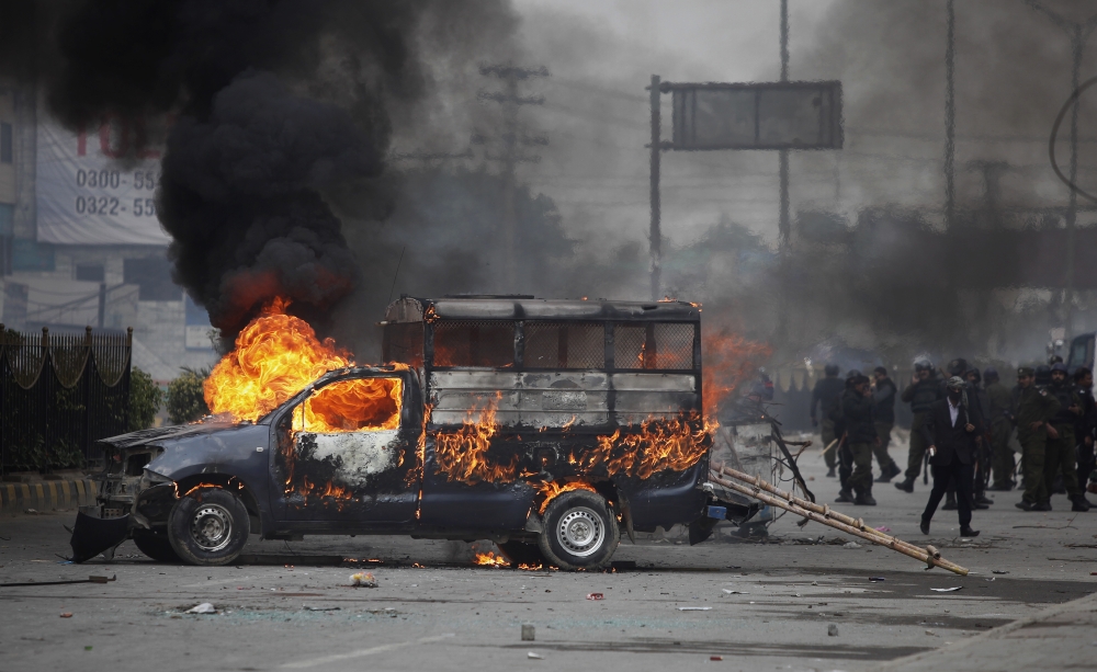 Pakistani police officers gather next to a burning police vehicle setting on fire by protesters during a clash in Islamabad, Pakistan,on Saturday. — AP