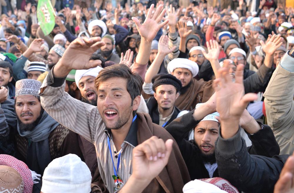 Pakistani supporters of a religious group shout slogans during a press conference of their leader Khadim Hussain Rizvi as he announces the end of the sit-in protest on a blocked flyover bridge during a press conference in Islamabad on Monday. — AFP