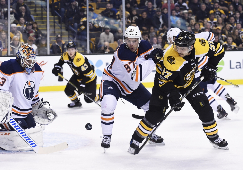 Edmonton Oilers center Connor McDavid (97) and Boston Bruins center Patrice Bergeron (37) battle for the puck in front of goalie Cam Talbot (33) during the first period at TD Garden. — Reuters