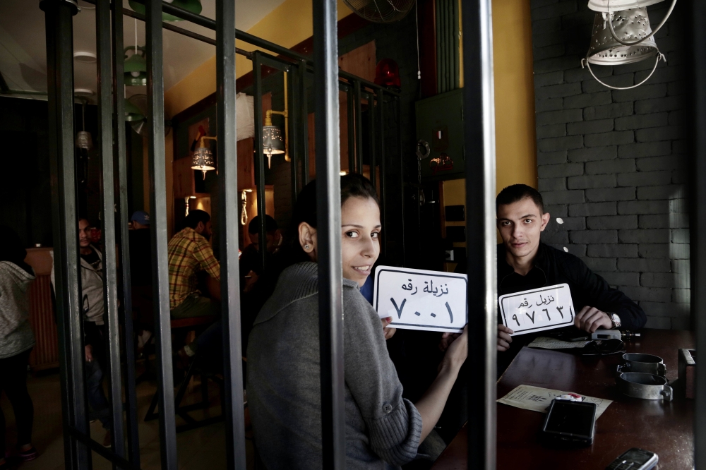 Customer Amr El Gohary, right, and his friend pose for a photograph with plastic plaques that translate to inmates with numbers, as they wait for their food, at prison-themed restaurant 'Food Crime' in the Nile Delta city of Mansoura, 110 kilometers (70 miles) north of Cairo, Egypt. — AP