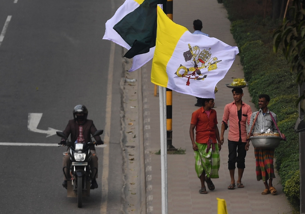 Vehicles pass by the flags of Bangladesh and Vatican City ahead of the visit of Pope Francis in Dhaka on Wednesday. — AFP
