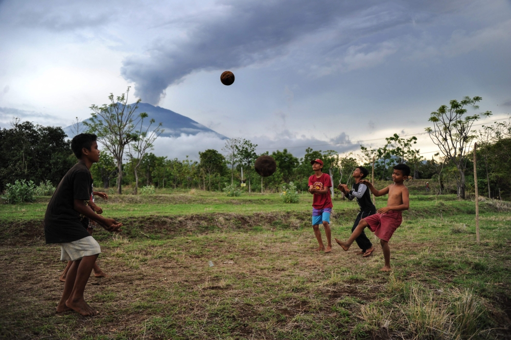 A farmer walks his ducks up a street as Mount Agung volcano erupts in the background, inside the evactuation zone in Karangasem Regency in Bali, Thursday. — Reuters