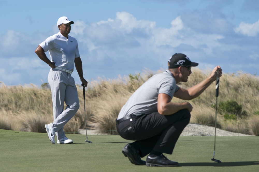Tiger Woods (left) watches Henrik Stenson (right) line up his putt on the first hole during the second round of the Hero World Challenge golf tournament at Albany, New Providence, The Bahamas, on Friday. — Reuters 