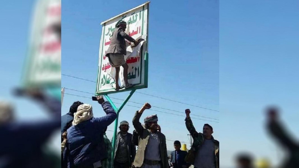 Yemenis tearing down a Houthi poster after revolting against the sectarian Iranian militia. — Courtesy Al Arabia English