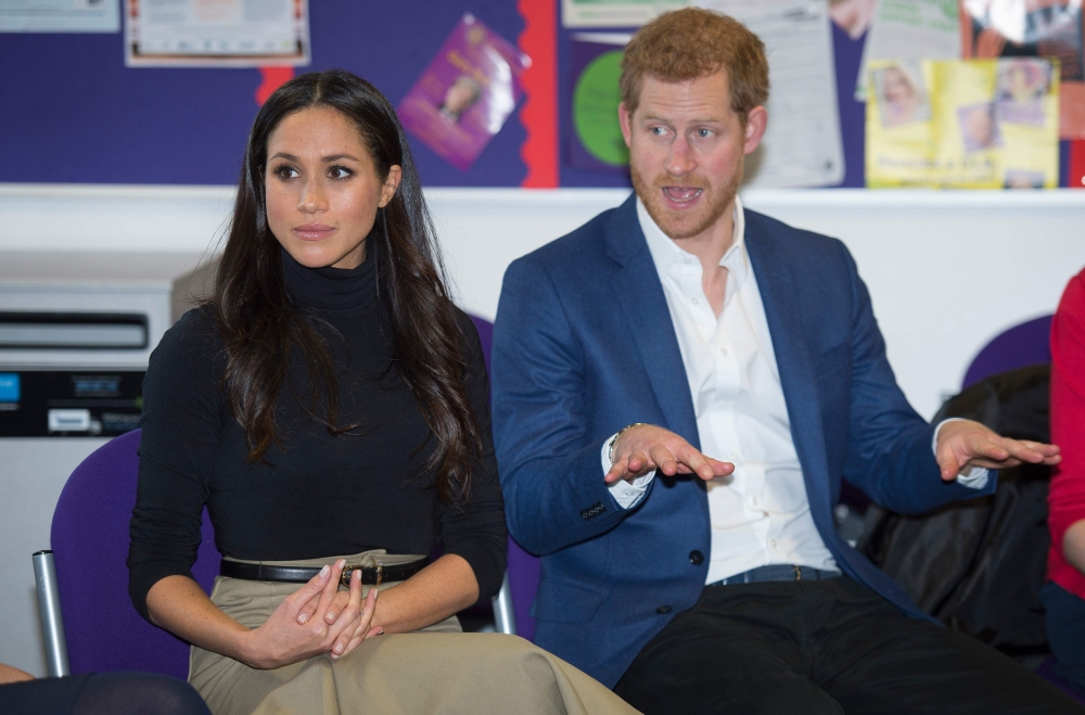 Britain's Prince Harry and his fiancee Meghan Markle gesture during their visit to Nottingham Academy in Nottingham, central England, on Friday. - AFP
