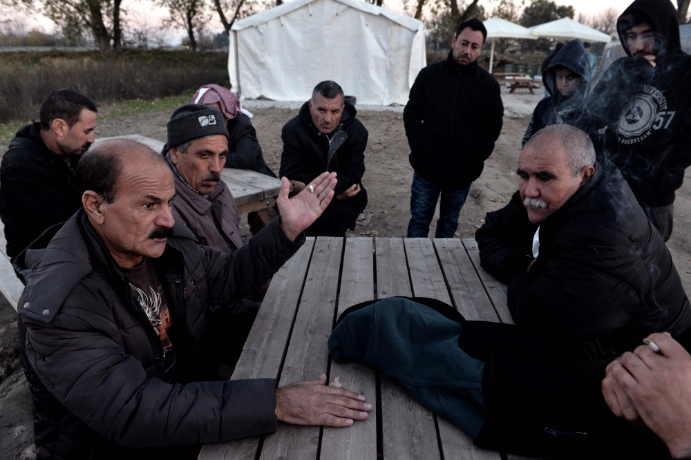 Yazidi refugees have a discussion as they sit outside at the Serres refugee camp, northern Greece. — AFP