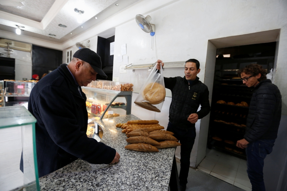 A customer buys bread at the shop of a bakery in Tunis, Tunisia. — Reuters