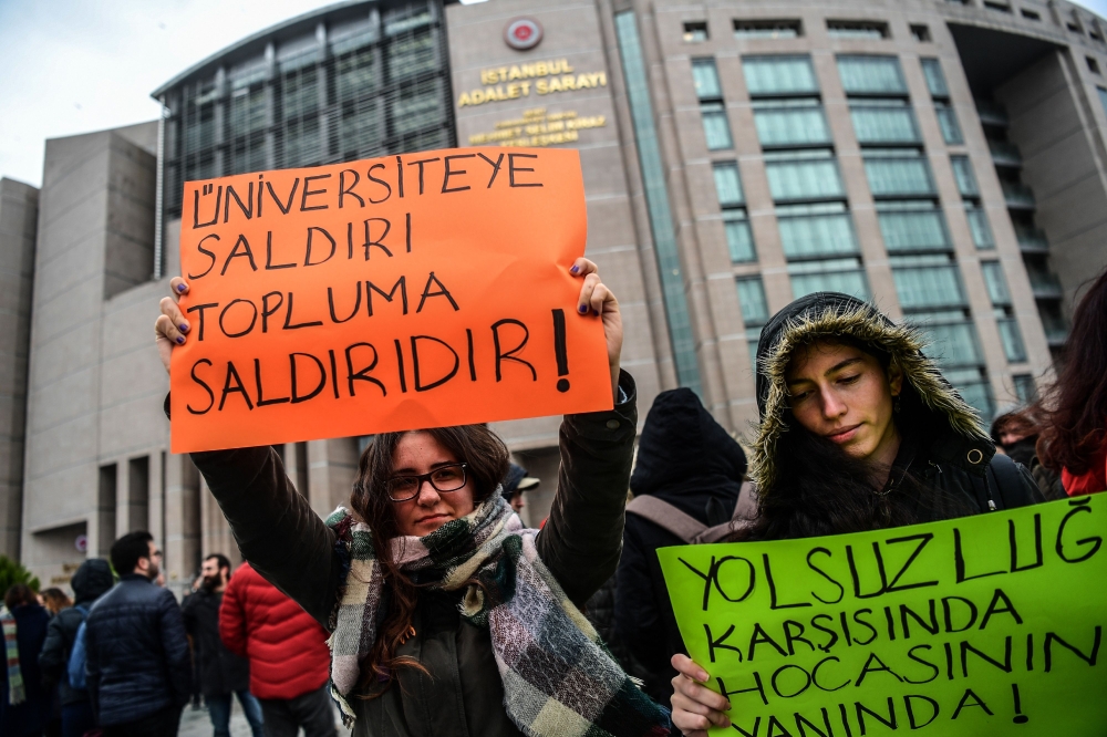 Protesters hold placards reading 