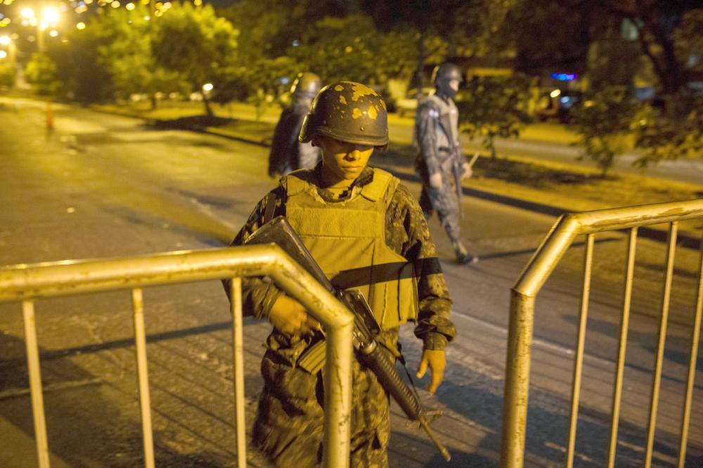 A soldier stands guard at a check point during a government imposed dawn-to-dusk curfew in Tegucigalpa, Honduras, late Tuesday. — AP