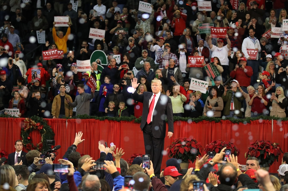US President Donald Trump waves as fake snow falls as he ends a rally at the Pensacola Bay Center on in Pensacola, Florida, on Friday. — AFP