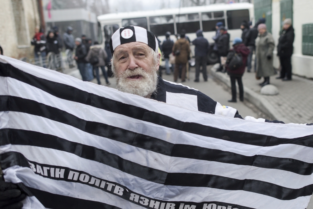 A demonstrator dressed like a prisoner stands near a Ukrainian police road block, during a protest held by supporters of former Georgian President Mikheil Saakashvili in a narrow street outside the police station where the former leader was taken, in Kiev, Ukraine, on Saturday. — AP