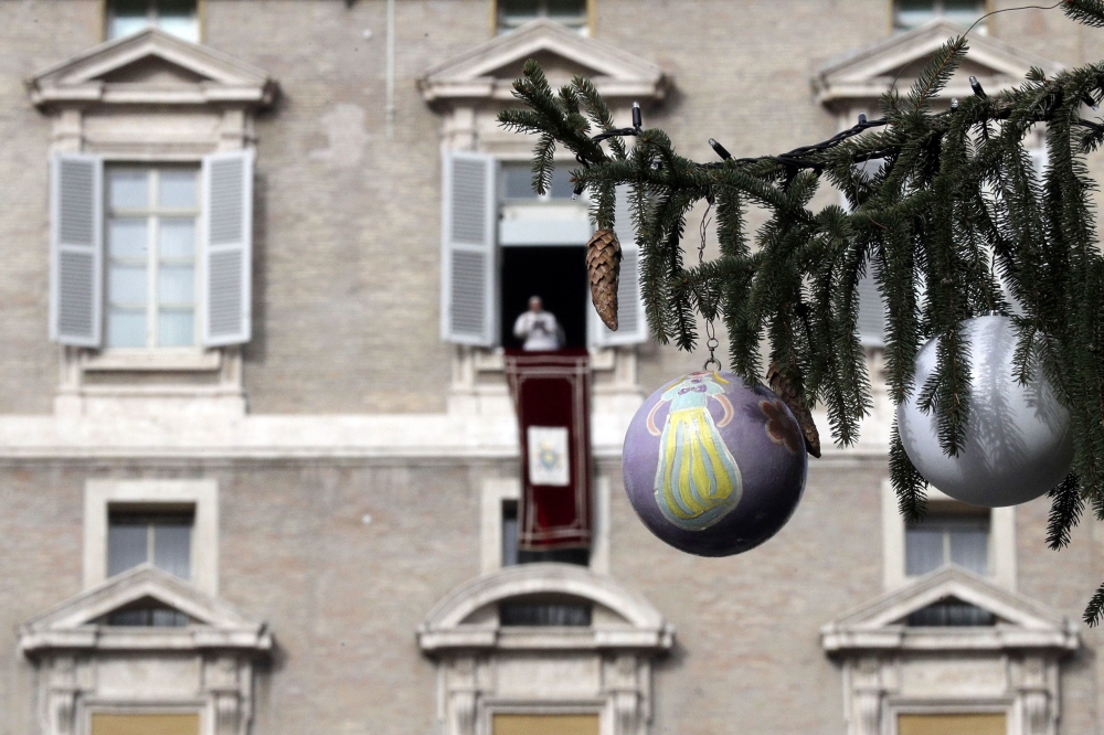 Pope Francis, framed by a branch of a Christmas tree, delivers his message during the Angelus noon prayer in St. Peter’s Square, at the Vatican, on Sunday. — AP