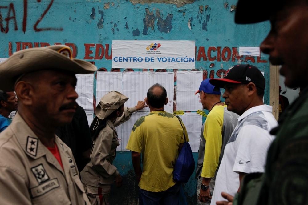 People check a list at a polling station during a nationwide election for new mayors, in Caracas, Venezuela, on Sunday. — Reuters