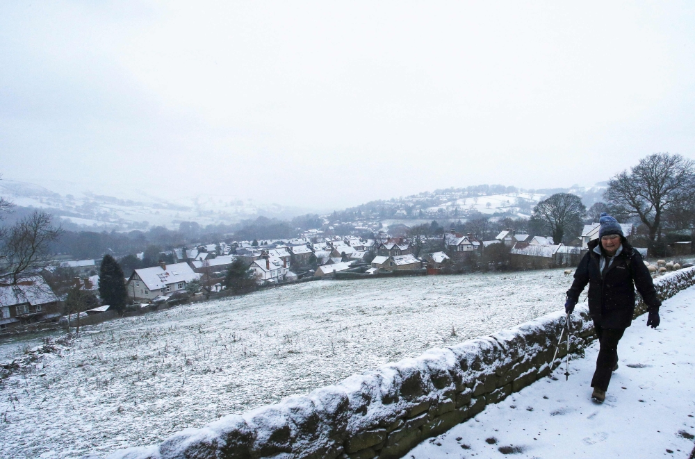A pedestrian walks in the snow near Castleton in Derbyshire, northern England, on Sunday. — AFP