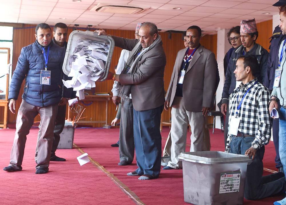 Nepali election commission officials pour ballot papers to count the votes in Kathmandu in this Dec. 8, 2017 file photo. — AFP