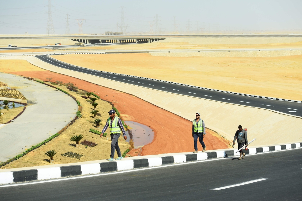 Construction workers walk on the side of a newly-built road in Egypt's new administrative capital, located 45 km east of Cairo. — AFP