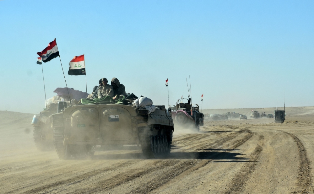 Members of the Iraqi forces and the Hashed Al-Shaabi (Popular Mobilization units) ride on infanty-fighting vehicles (IFV) near the Iraqi-Syrian border, about 80 km (about 50 miles) west of the border town of Al-Qaim. — AFP