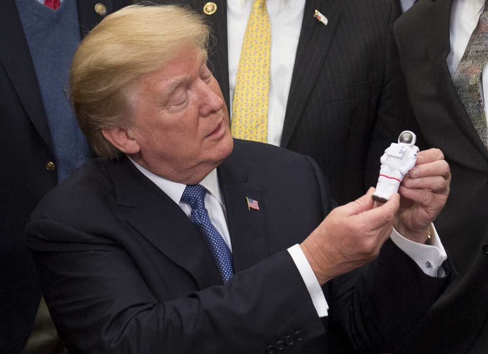 TOPSHOT - US President Donald Trump holds an Astronaut toy after a signing ceremony for Space Policy Directive 1, with the aim of returning Americans to the Moon, in the Roosevelt Room at the White House in Washington, on Monday. — AFP