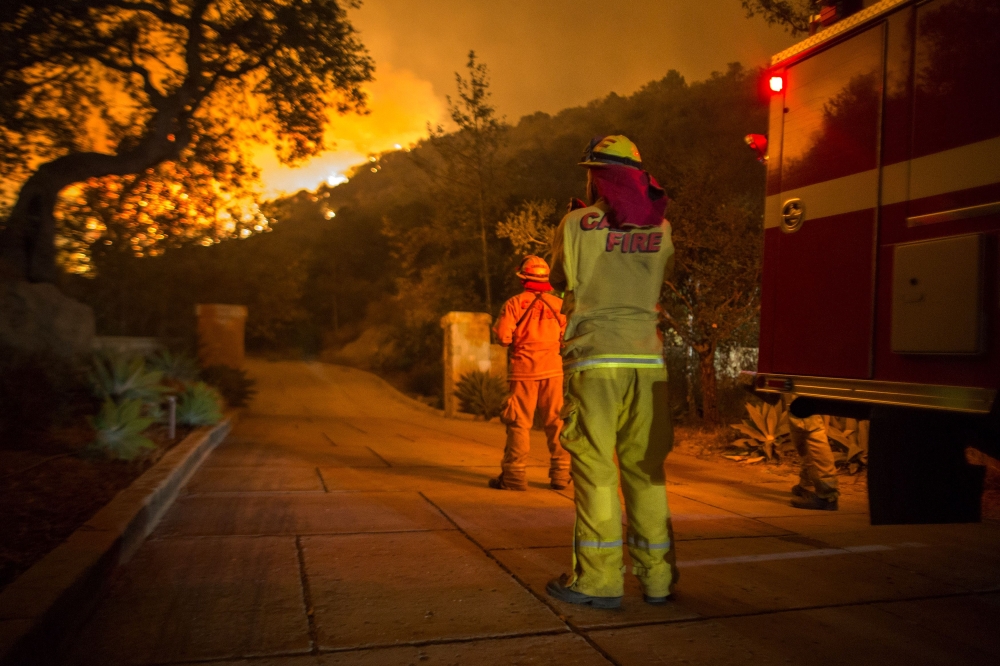 Firefighters watch flames as the Thomas Fire approaches homes in Montecito, California, on Tuesday. — AFP