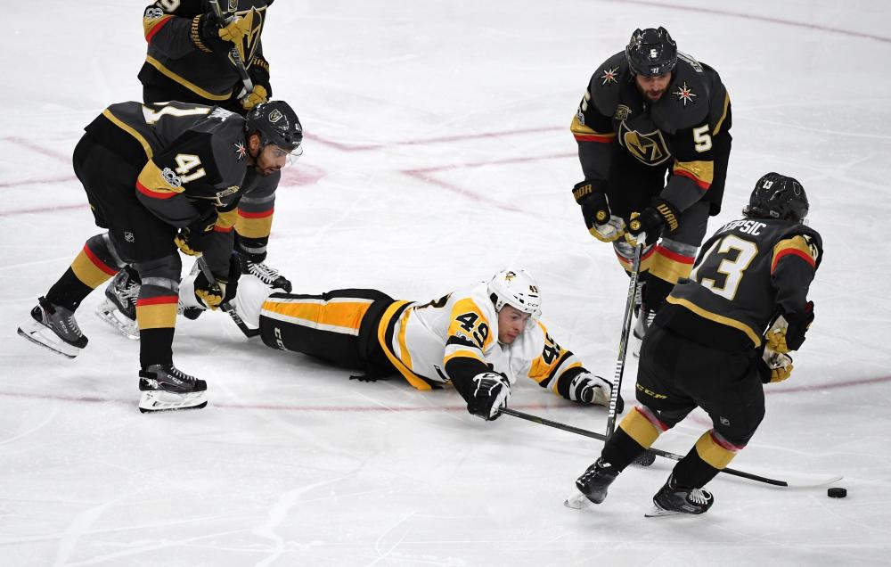 Dominik Simon of the Pittsburgh Penguins dives on the ice as he tries to control the puck against Pierre-Edouard Bellemare (No. 41), Deryk Engelland  (No. 5) and Brendan Leipsic (No. 13) of the Vegas Golden Knights during their NHL game at T-Mobile Arena in Las Vegas Thursday. — AFP
