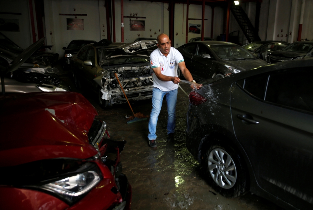Mohamed Shaheen, owner of El Faqyier (The Poor), a crash-damaged vehicles and second-hand car shop, washes a new arrival car in Cairo, Egypt. — Reuters