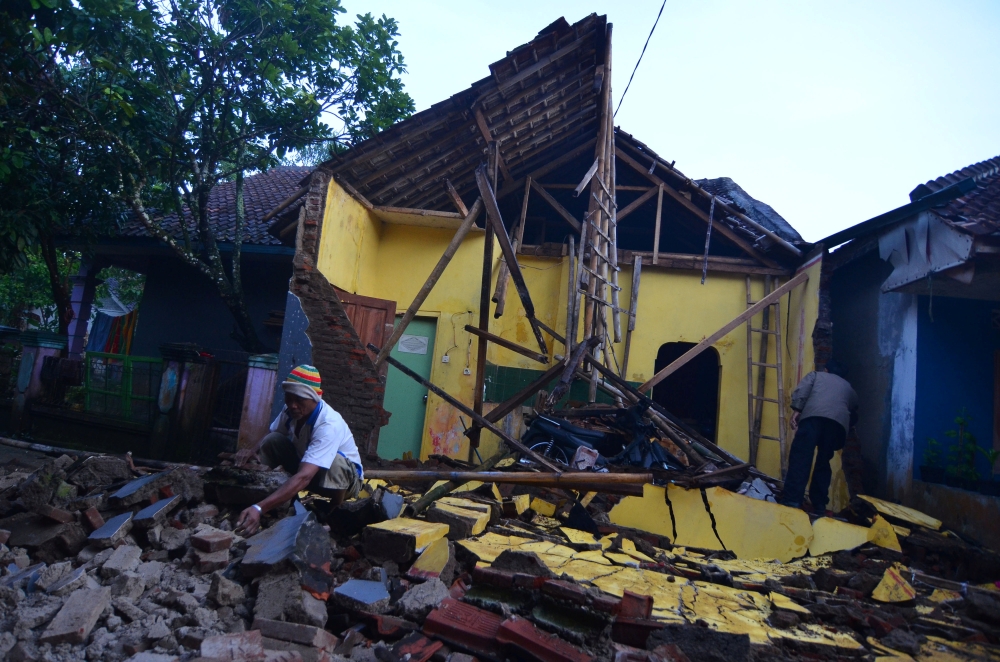 A man cleans up the wreckage of a house damaged by an earthquake in Sumelap Village, Tasikmalaya City, West Java, Indonesia, on Saturday. — Reuters