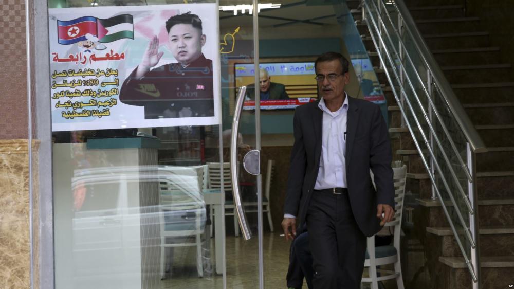 A Palestinian customer walks out of a shawarma restaurant with a poster of North Korean leader Kim Jong Un at the entrance of it in Jebaliya refugee camp in Gaza Strip on Friday. - AP
