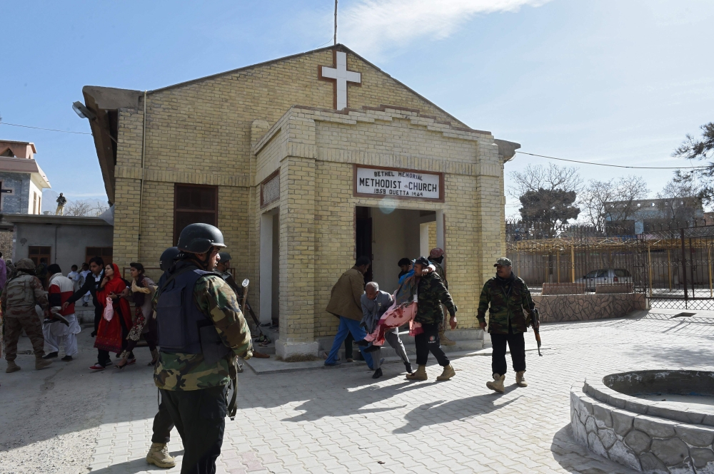 Pakistani security personnel rescue an injured woman after suicide bombers attacked a Methodist church during a Sunday service in Quetta on Sunday. — AFP