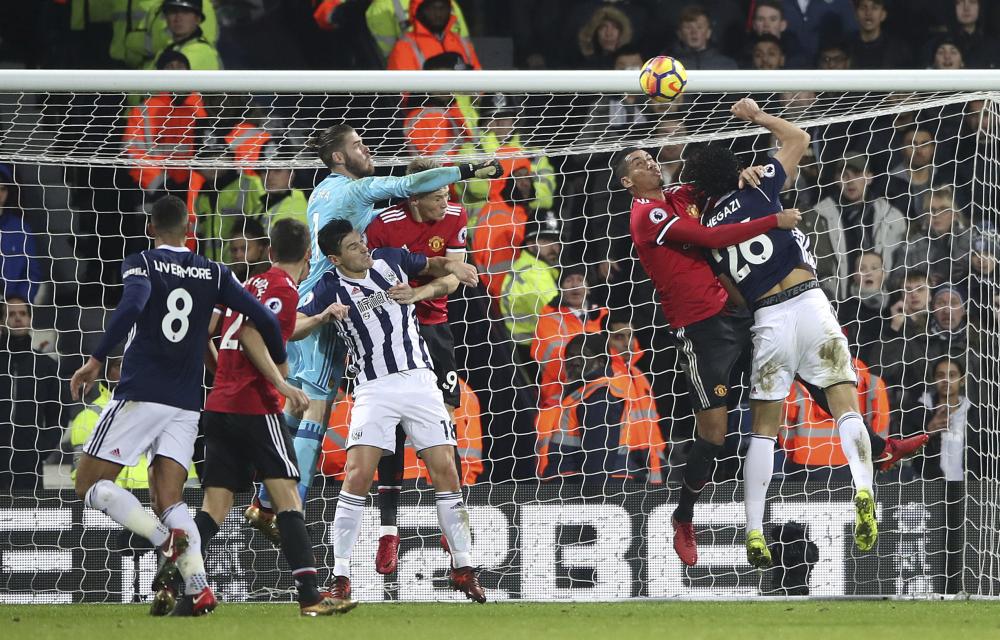 Manchester United’s goalkeeper David De Gea punches the ball clear, under pressure from West Bromwich Albion's Gareth Barry during their English Premier League soccer match at The Hawthorns, West Bromwich, England, Sunday. — AP