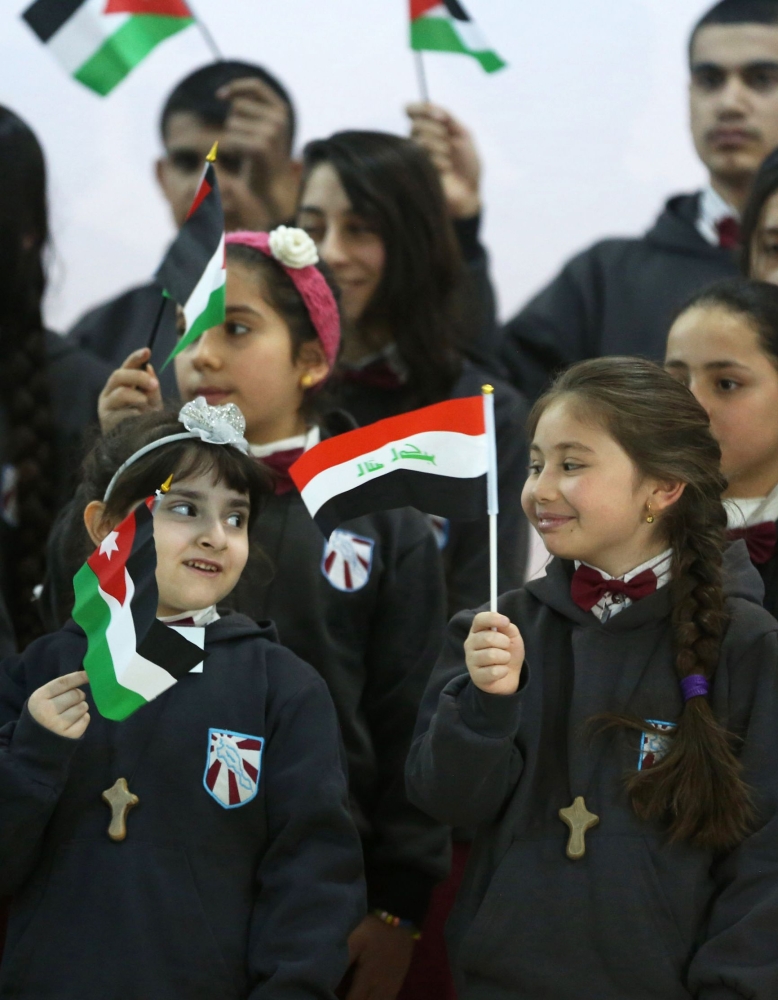 Iraqi Christian students wave Jordanian (L) and Iraqi (R) flags as they line up at the Latin Patriarchate school in the Marka district in the eastern part of the capital Amman. Some 200 Iraqi Christian student refugees in Jordan take night classes at the Marka Latin Church, most of whom fled northern Iraq in 2014 following its takeover by Daesh group militants. — AFP