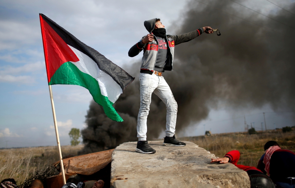 A Palestinian demonstrator uses a slingshot to hurl stones toward Israeli troops during clashes in Gaza City at a protest against US President Donald Trump's decision to recognize Jerusalem as the capital of Israel. — Reuters